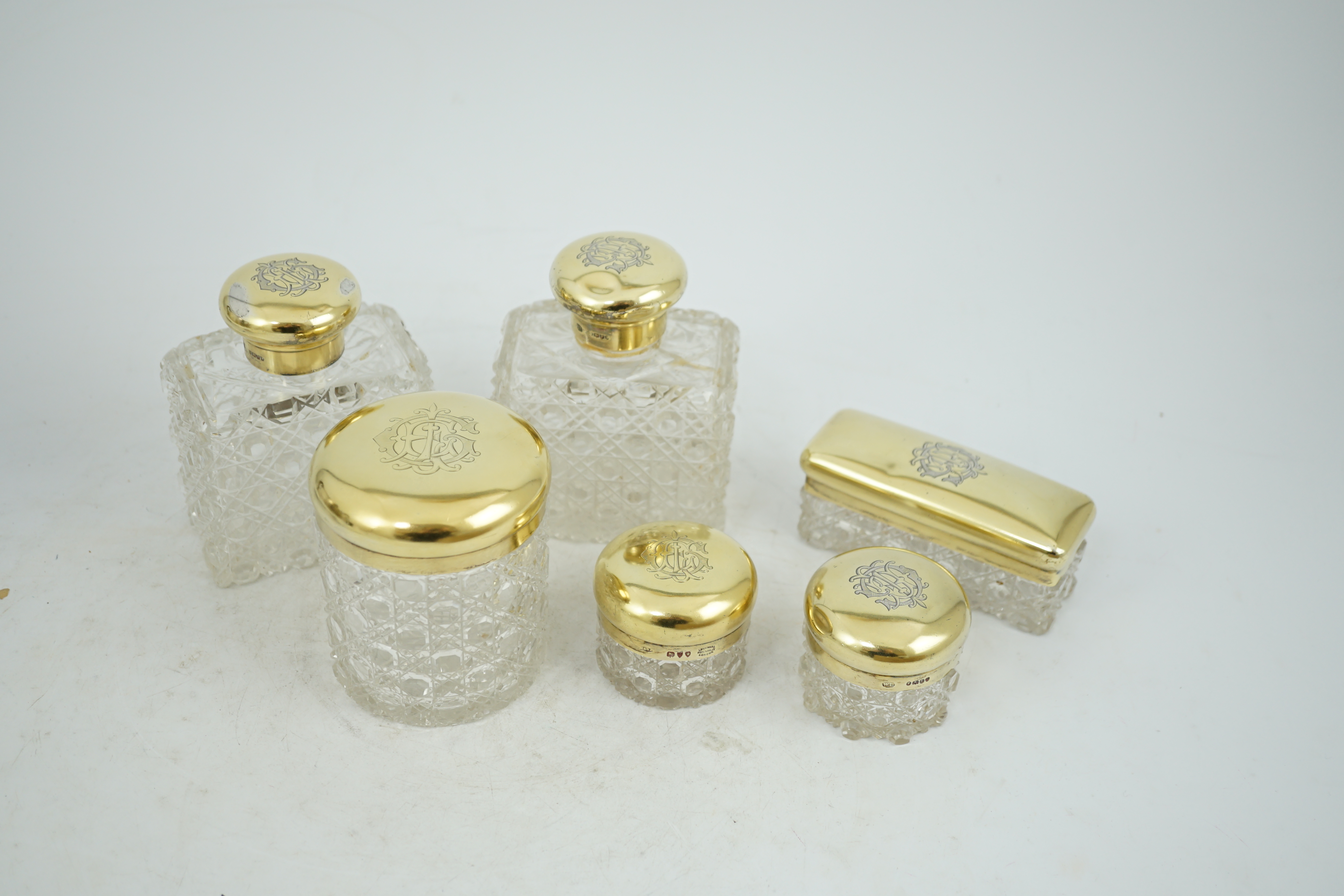 A matched suite of six late Victorian silver gilt mounted cut glass toilet jars two by Charles & George Asprey, London, 1893, tallest 12.2cm.